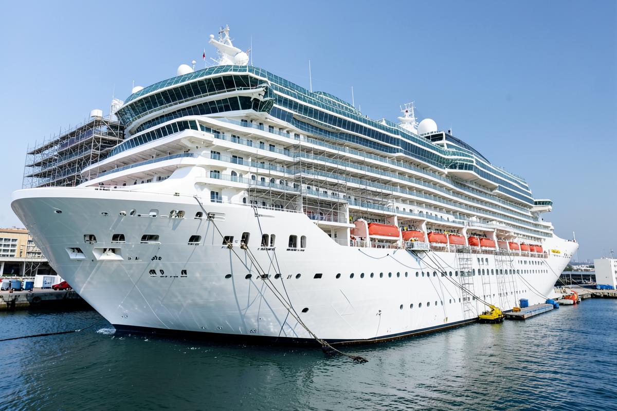 Cruise ship docked at port with cleaning equipment along the hull
